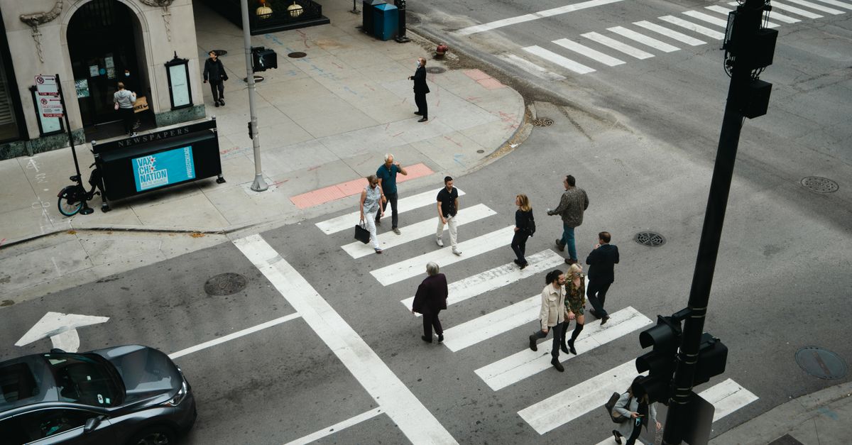 Aerial view of people crossing a city street at a pedestrian crosswalk.